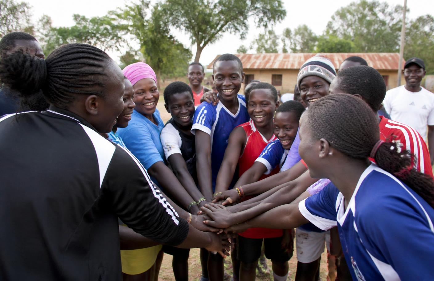 Community sports team huddling together, hands joined in the centre